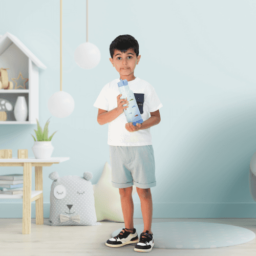 Boy standing in a child's bedroom, holding the Bentotss Travel Trot Light Blue Sipper bottle