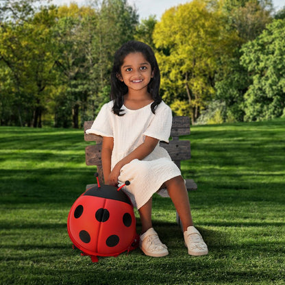 Girl sitting outdoors on a patch of grass, wearing the red Bentotss Bugs & Bites Bento Bag backpack