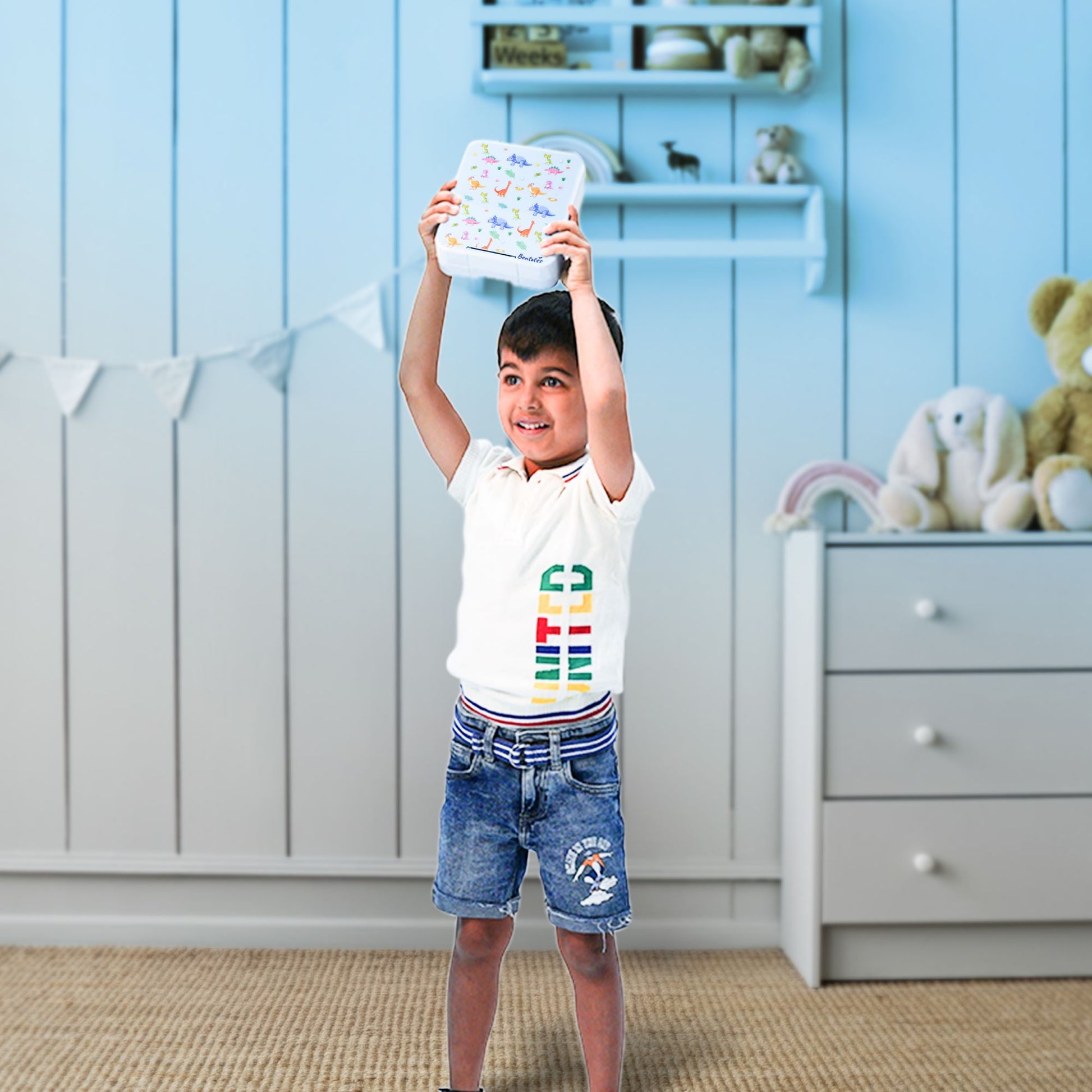 Boy holding up the Bento dinosaur themed lunchbox by Bentotss in a bright room setting